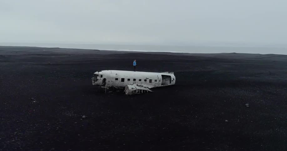 Someone is standing on a crashed abandoned plane in the middle of a barren landscape