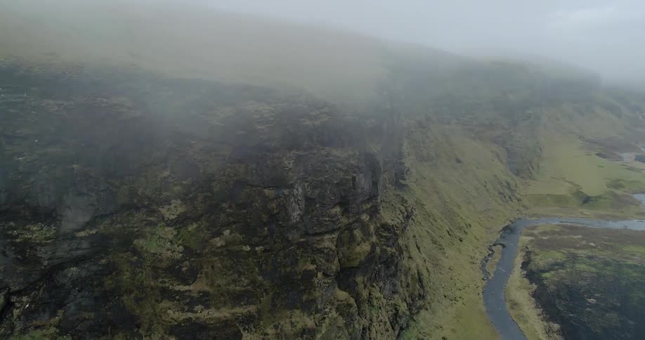 The fog is rolling over the cliff near the shore