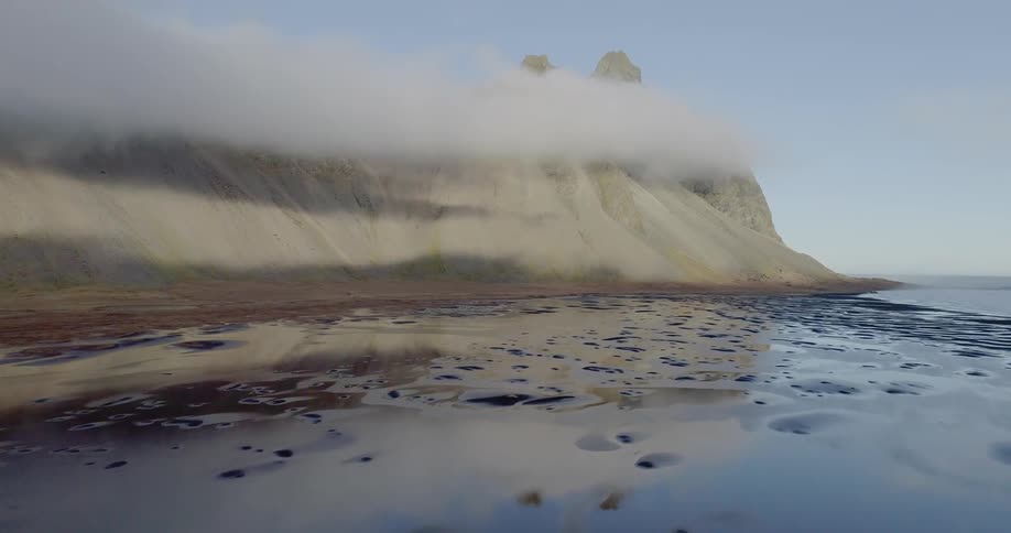 The clouds touch the top of the hills on the shore