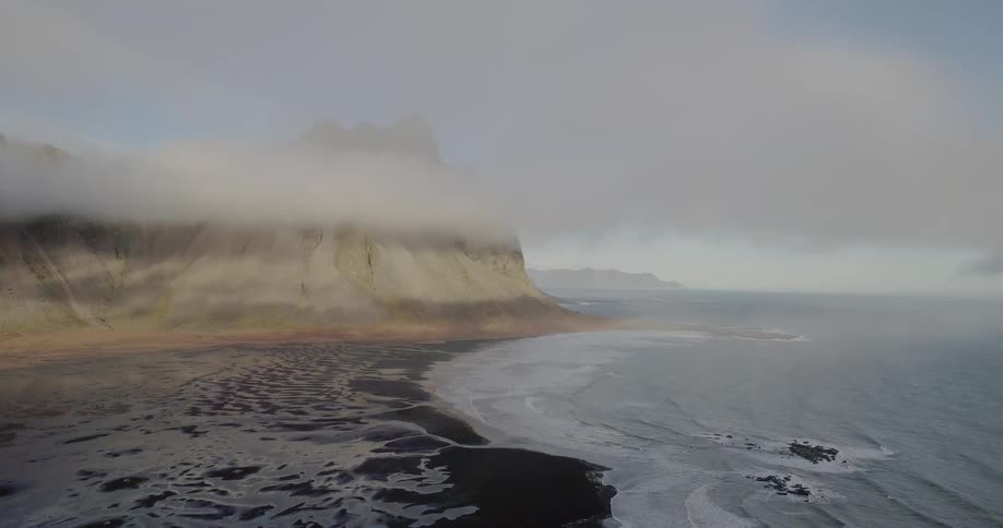 The shore has rough waves on a foggy day