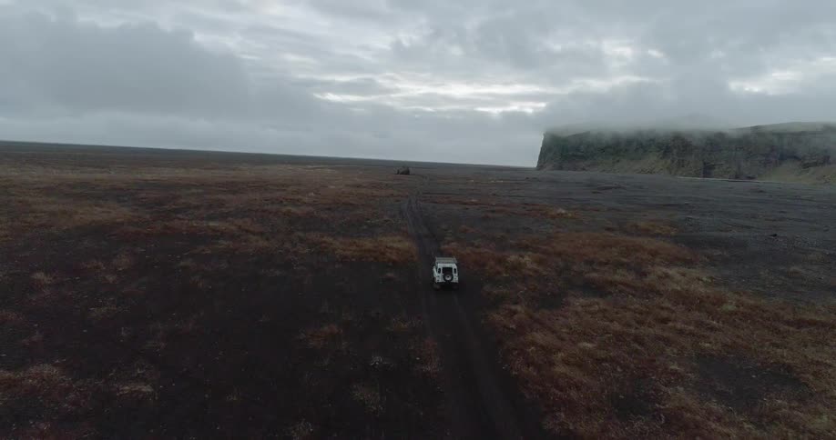Jeep traveling on road crossing flatland wilderness on cloudy day