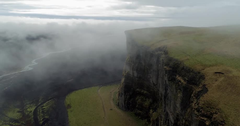 Mist floats over a high cliff near a creek