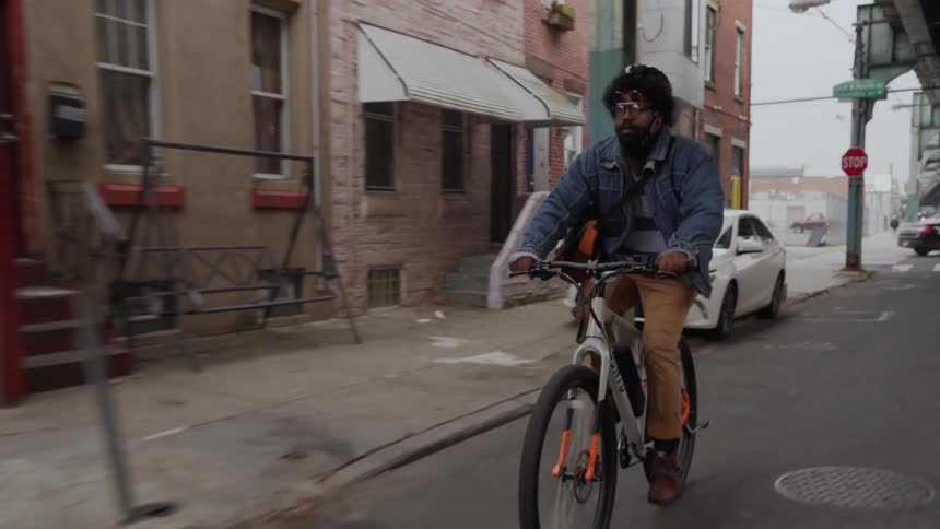 A man rides his bicycle fast down the city street