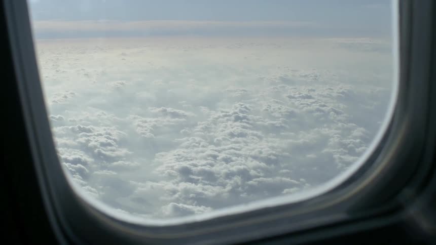 Airplane flies over the white clouds under a blue sky