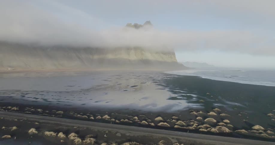 The shore is lined with stones and a cliff at the end