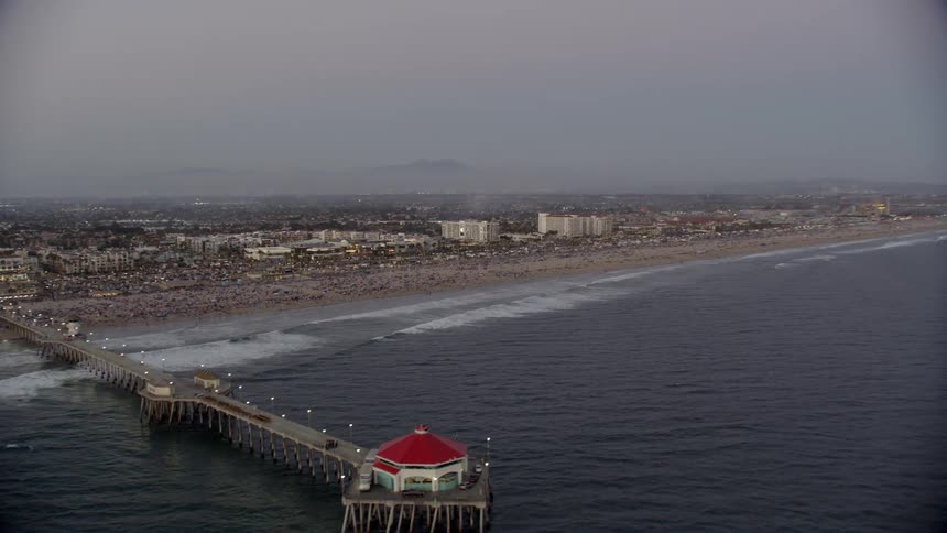 A gazebo sits at the end of the pier as waves come to shore