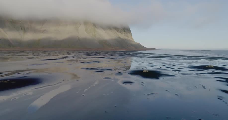 Clouds float above wet sand on a beach