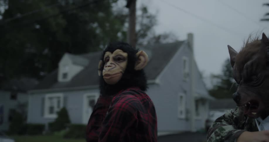 Teenagers in animal masks throw eggs at a house