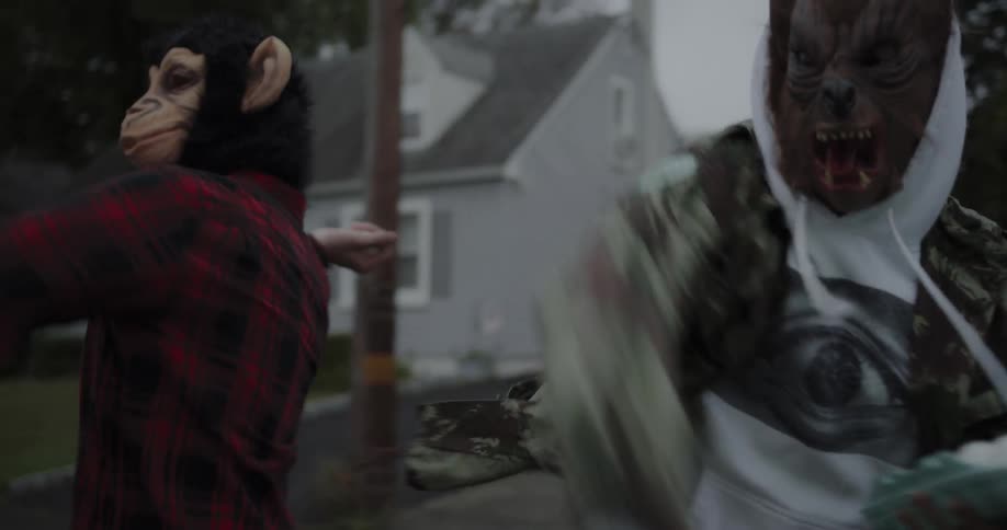 Two kids with halloween masks grab eggs and throw them
