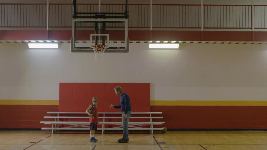 A man yells at a boy on a basketball court