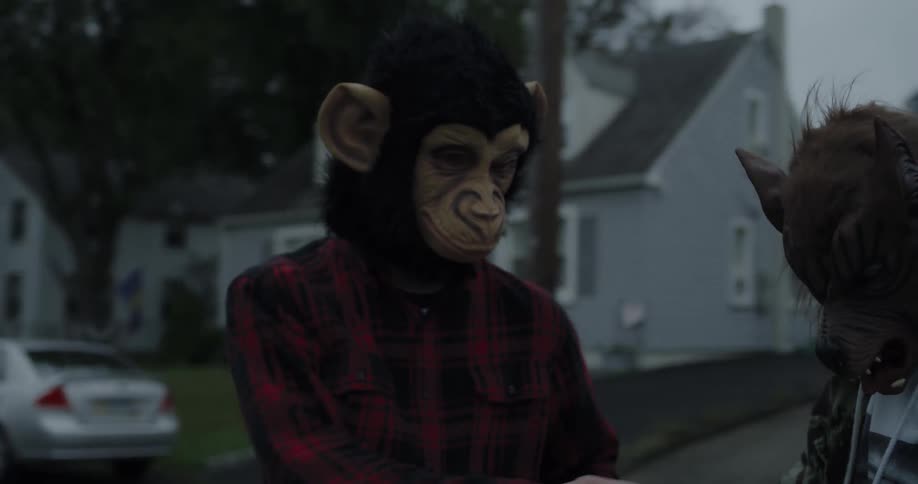 Two people wearing animal masks are throwing eggs at house