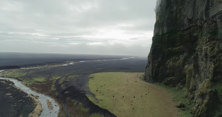 Birds fly over a creek near a mountain