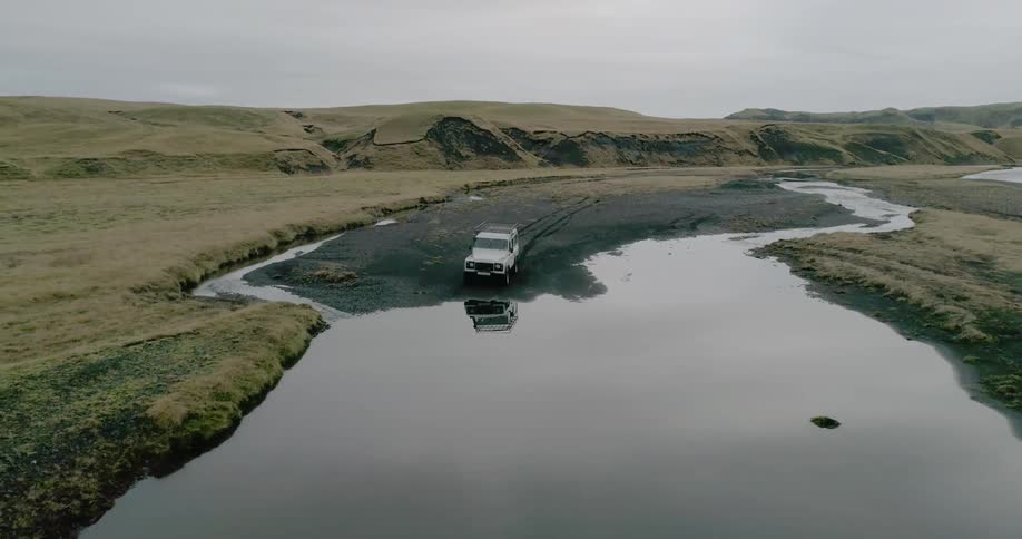 A vehicle drives through water in a rural field
