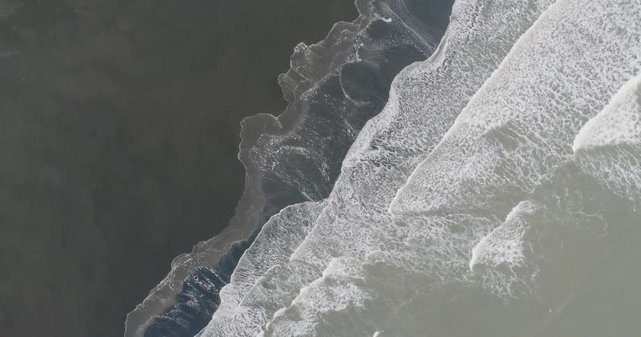 Foamy waves crash into the sandy beach