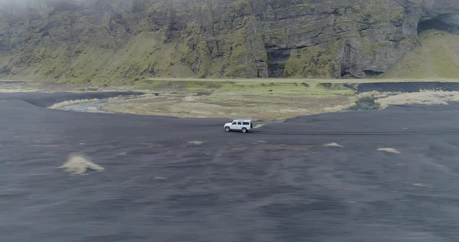 A vehicle rides fast on the terrain near a mountain