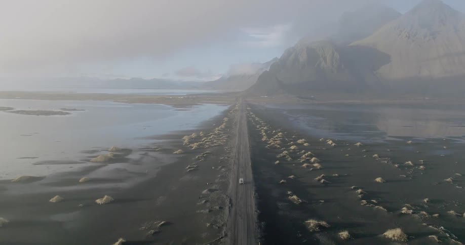 A truck travels on a dirt road on the shore