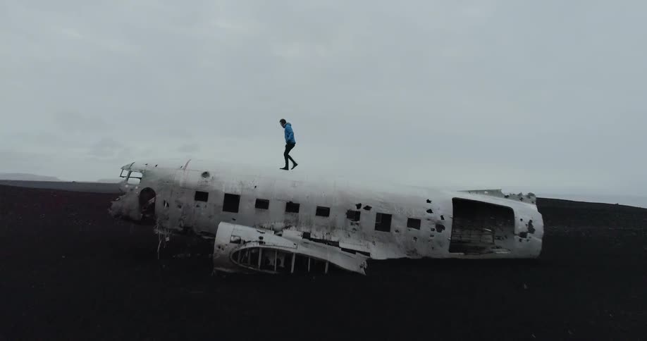 Man walks on top of an airplane in a field