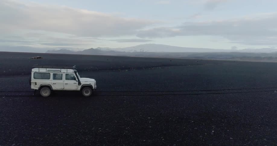The white vehicle drives fast over the dark fields