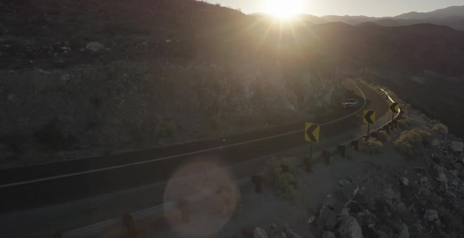 The sun sets over a mountain road