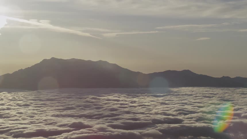 Mountaintops rise above a heavy layer of clouds near sunset