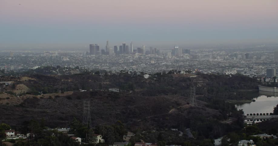 Flying over a neighborhood on a hillside with los angeles in the background