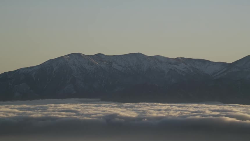 Thick layer of clouds hovering beside large mountain