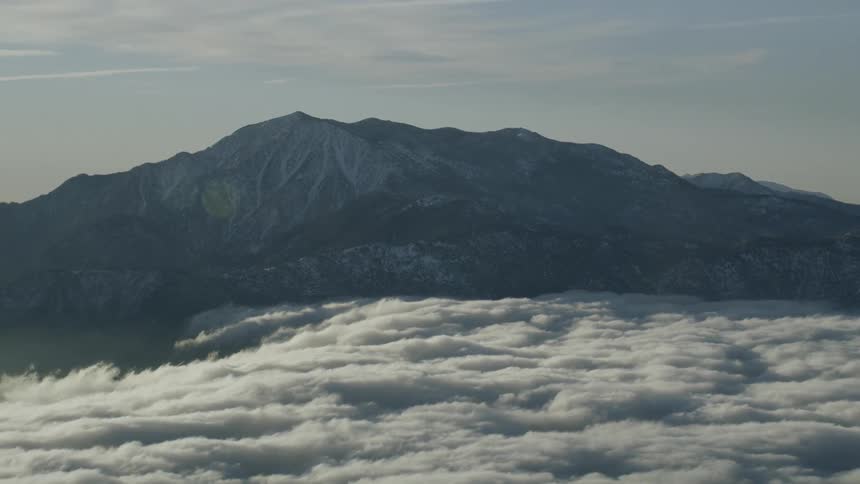 Clouds in a valley with a large mountain rising above