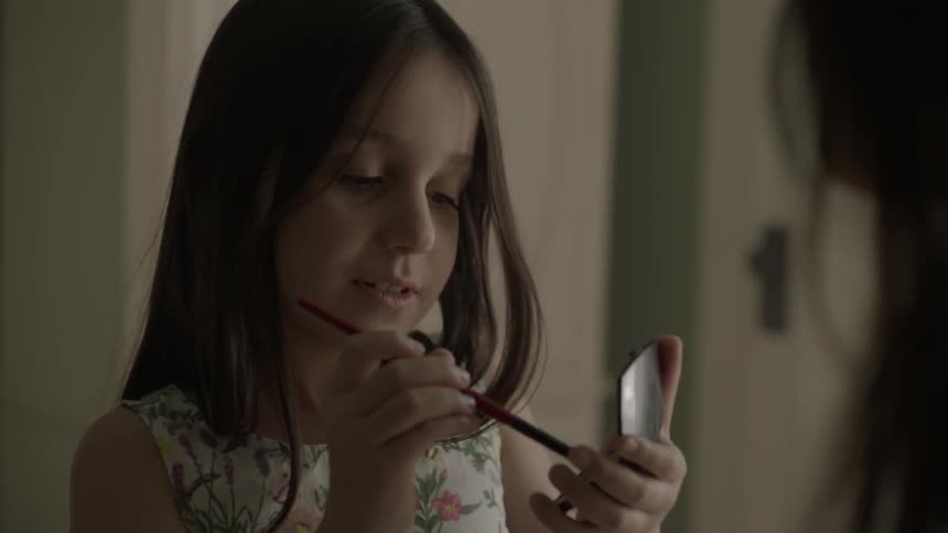 A child is applying makeup to a woman
