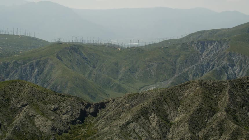 Windmills are rotating on top of a tall mountain