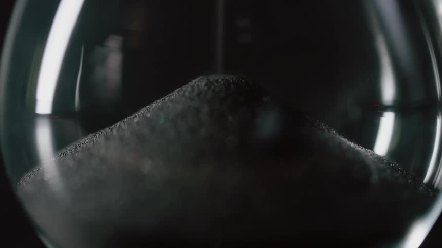 Sand slowly pours into the hourglass