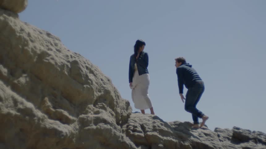 A man and woman climb rocks on a sunny day