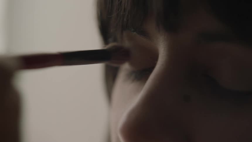 Woman getting makeup applied to her eyelids