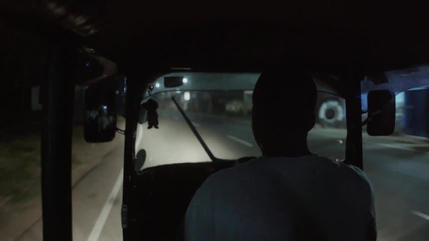 A man is driving a vehicle down the street fast at night