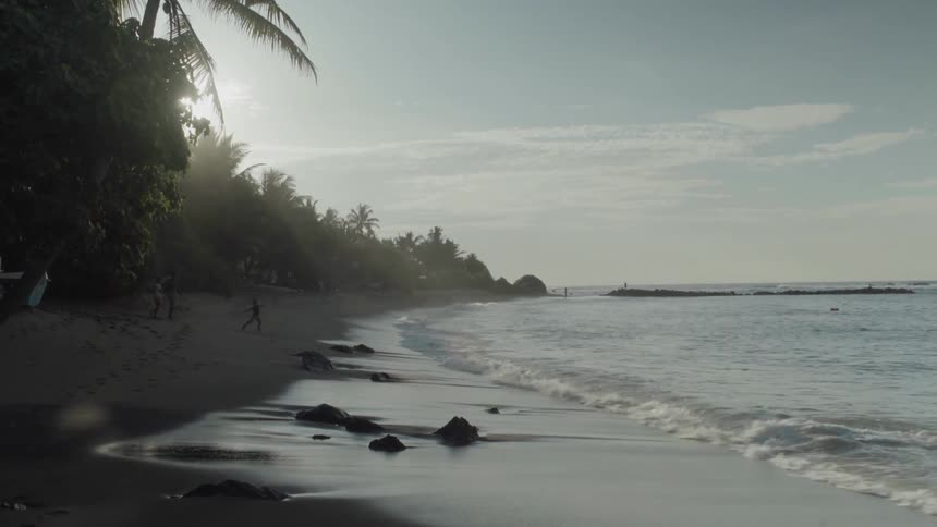 Small waves coming ashore on a narrow beach near sunset