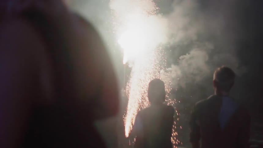 People hold sparklers and shoot off fireworks