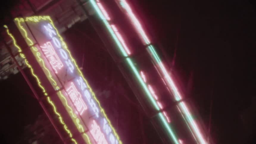 Neon lights hang above the city street at night
