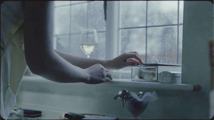 A woman looks at the jewelry in a box on the sill