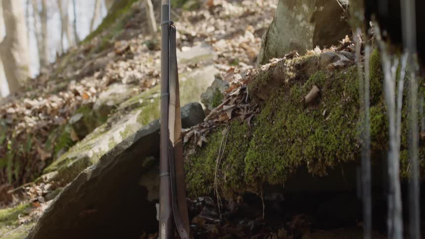 A rifle rests against a rock ledge
