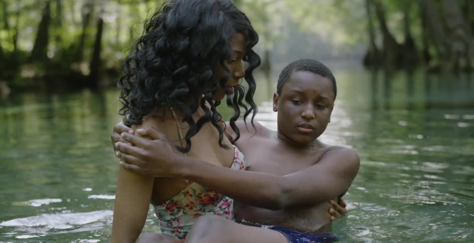 A woman is teaching a boy how to swim outside in a natural setting
