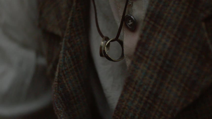 A person has rings hanging from a rope around their neck