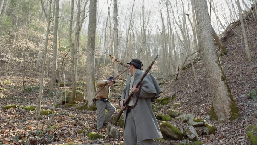 Confederate soldiers are going on alert as they patrol through a wooded area in daylight