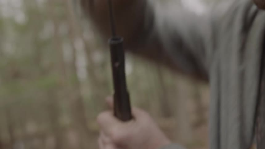 A confederate soldier is reloading his weapon after firing it outside in daylight