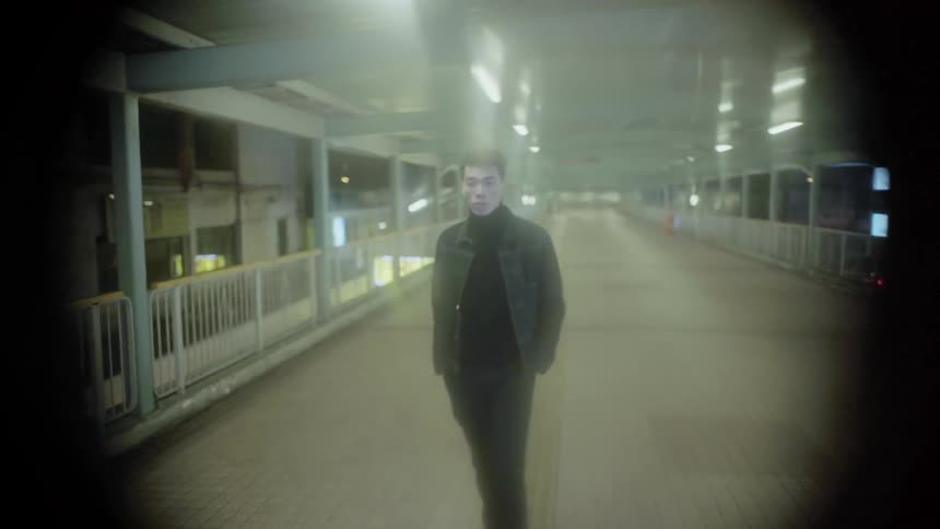 A man is walking on an elevated walkway in a city at night