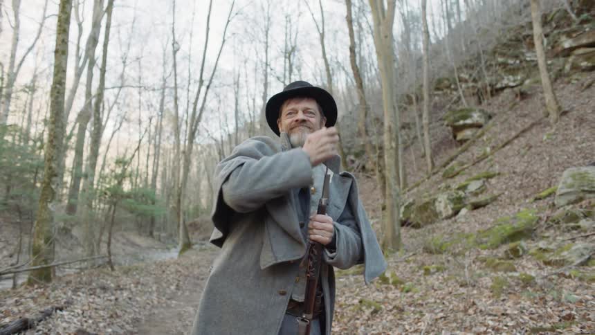 A man loads an old rifle in a forest