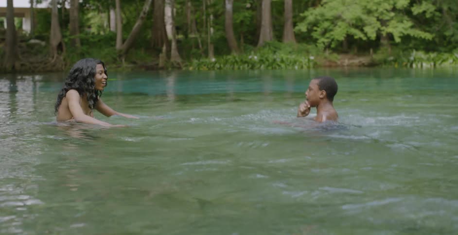 Two women wade in a lake with a child