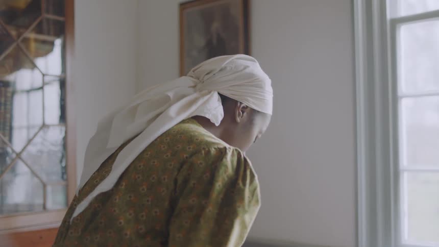 A woman dressed as a servant walks in the dining room