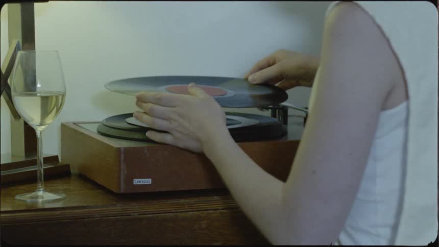 A woman puts a vinyl record on a record player