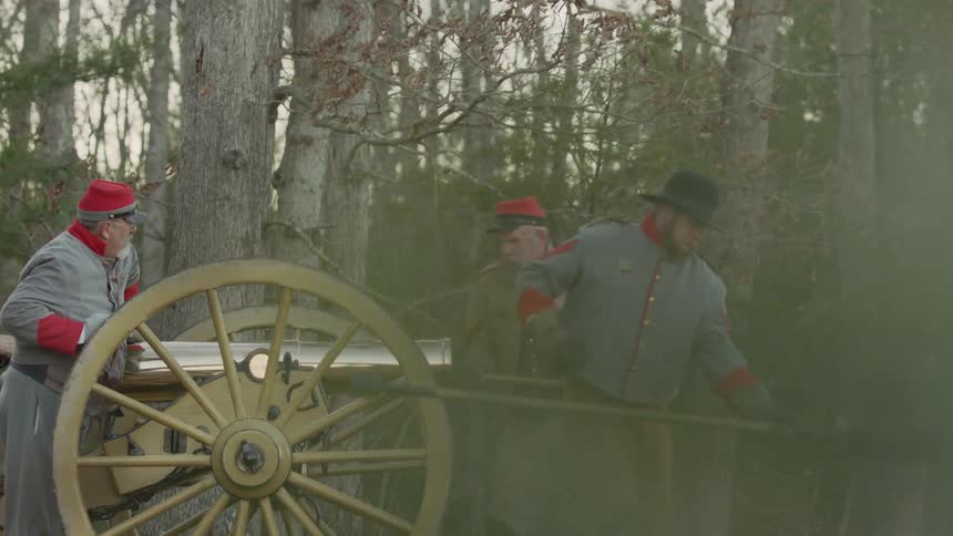 Soldiers are firing a canon outside in a forest in daytime