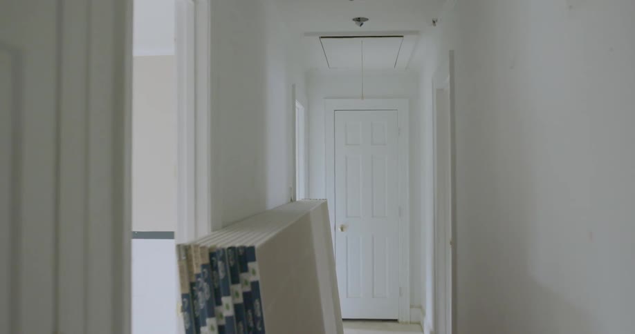 Drywall panels are stacked against a hallway wall