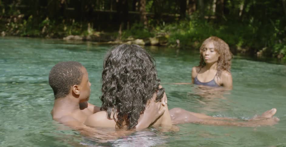 A woman carries a man into the water